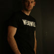 Load image into Gallery viewer, Man wearing cycling t-shirt in black with wearwell logo in dark room