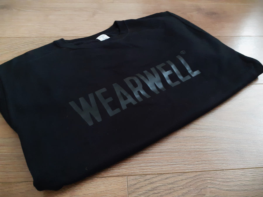 Black wearwell cycling top folded on wooden floor