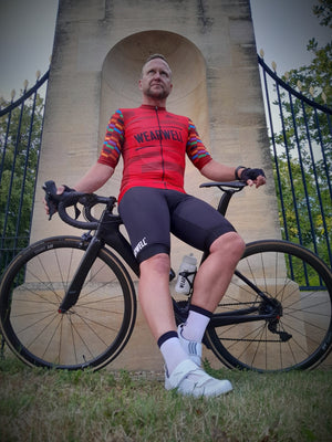 Man with road racing bicycle and wearwell gambler cycling jersey in red and cycling shorts